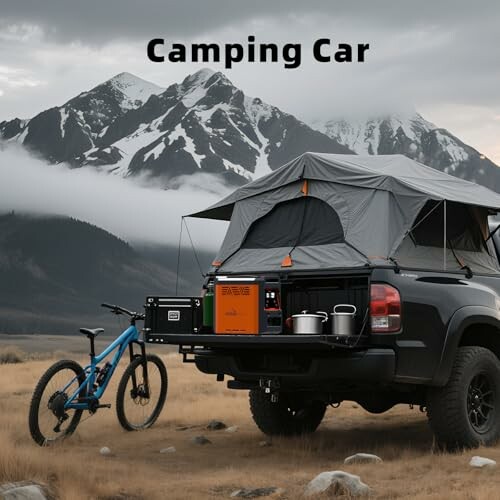 Truck with rooftop tent and camping gear near mountains.