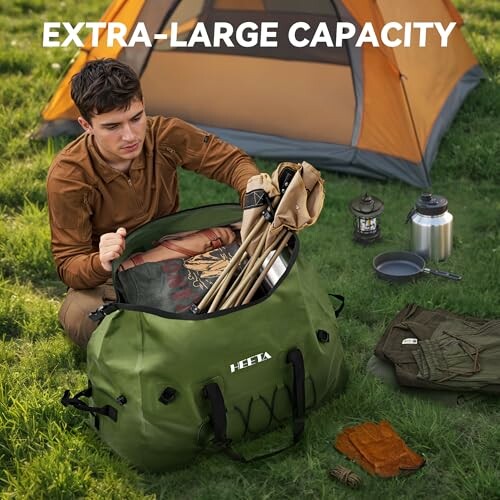 Person packing camping gear into a large green bag near a tent.