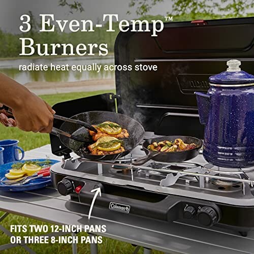Camping stove with three burners cooking food outdoors.