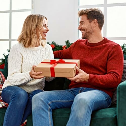 A couple exchanging a gift on a sofa with holiday decor in the background.