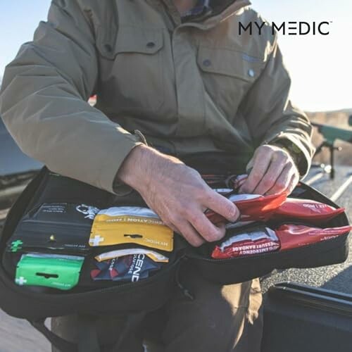 Person organizing a first aid kit outdoors.