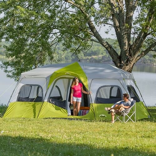 Family enjoying a large green and gray camping tent by a lake.