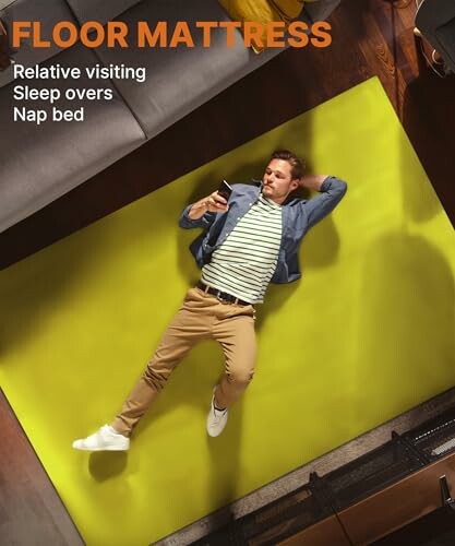 Man lying on a floor mattress using a phone, showcasing the comfort of the 3 Inch Memory Foam Camping Mattress.
