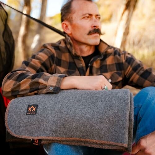 Man sitting outdoors with a gray blanket on his lap.