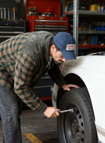 Mechanic checking car tire with a wrench in a garage.