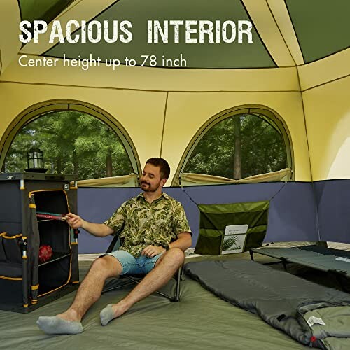 Man sitting inside a spacious tent with camping gear.