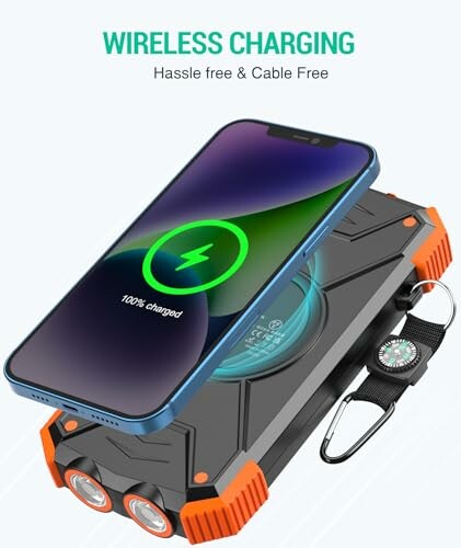 Smartphone wirelessly charging on rugged power bank with compass and flashlight.